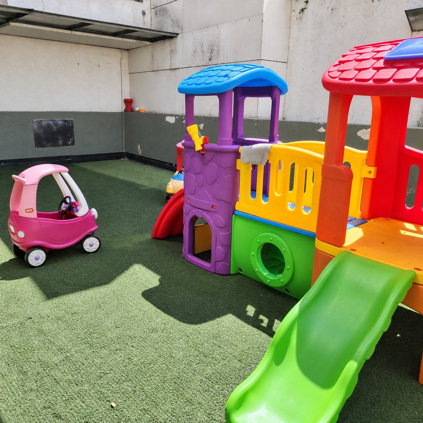 Patio del jardín con casitas de juego de colores, resbalín y autitos