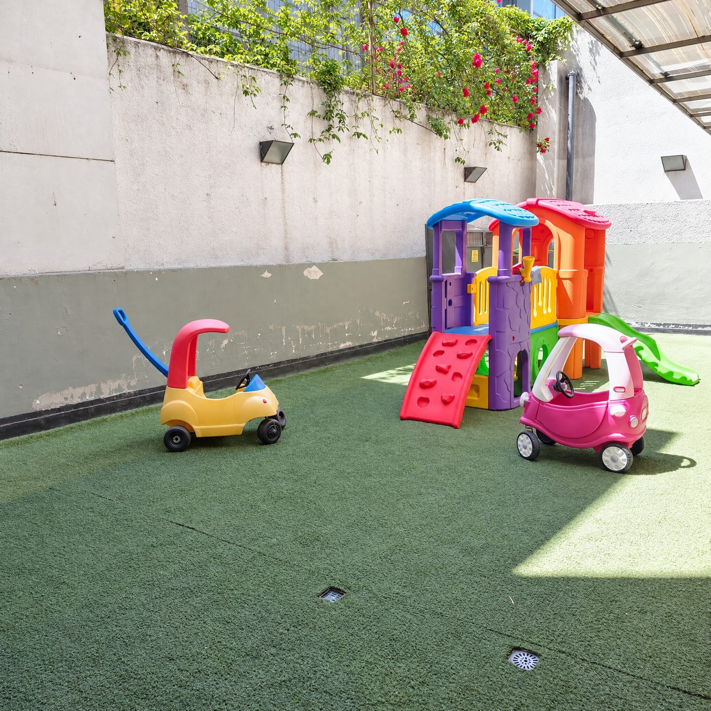 Patio con pasto sintético, casitas de juego y autitos