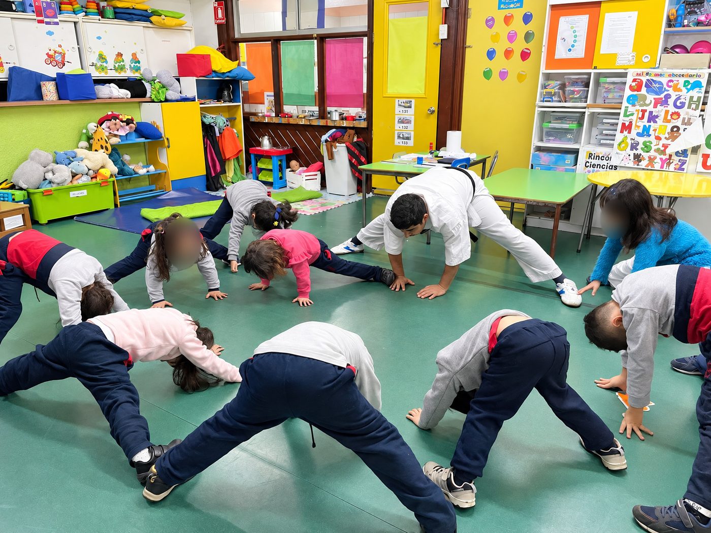 Niños y niñas estirándose en el taller de psicomotricidad junto a su profesor